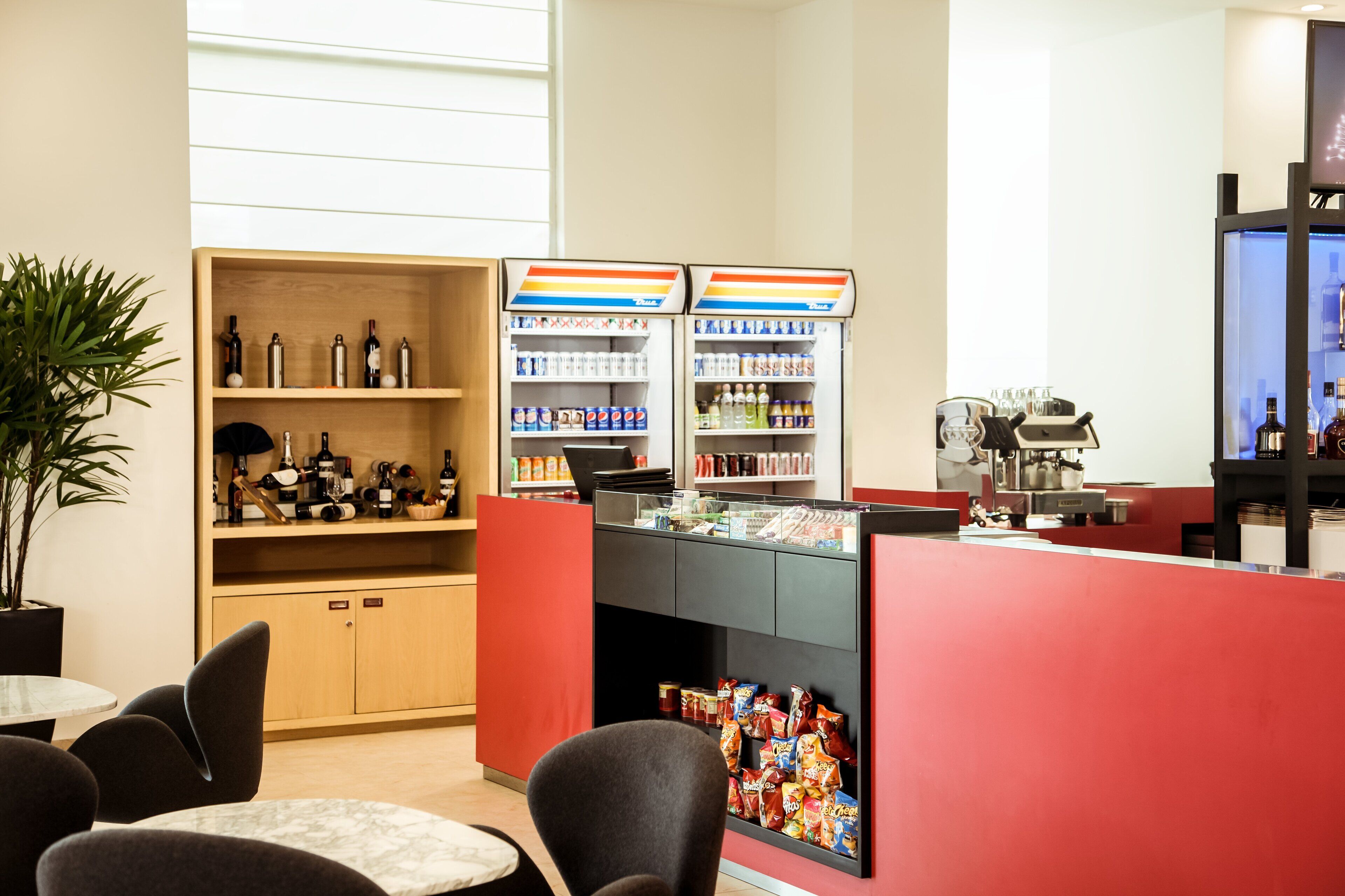 A modern bar area with seating, a beverage dispenser, and a coffee machine.