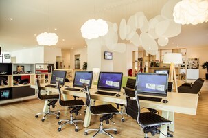 A modern office space with multiple desks, ergonomic chairs, and computers.