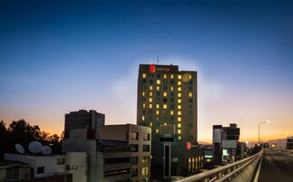 Un immeuble à plusieurs étages, sur lequel on peut voir une enseigne bien visible indiquant « Fiesta Inn ». Il présente une architecture moderne, avec un toit plat et une série de fenêtres régulièrement espacées.