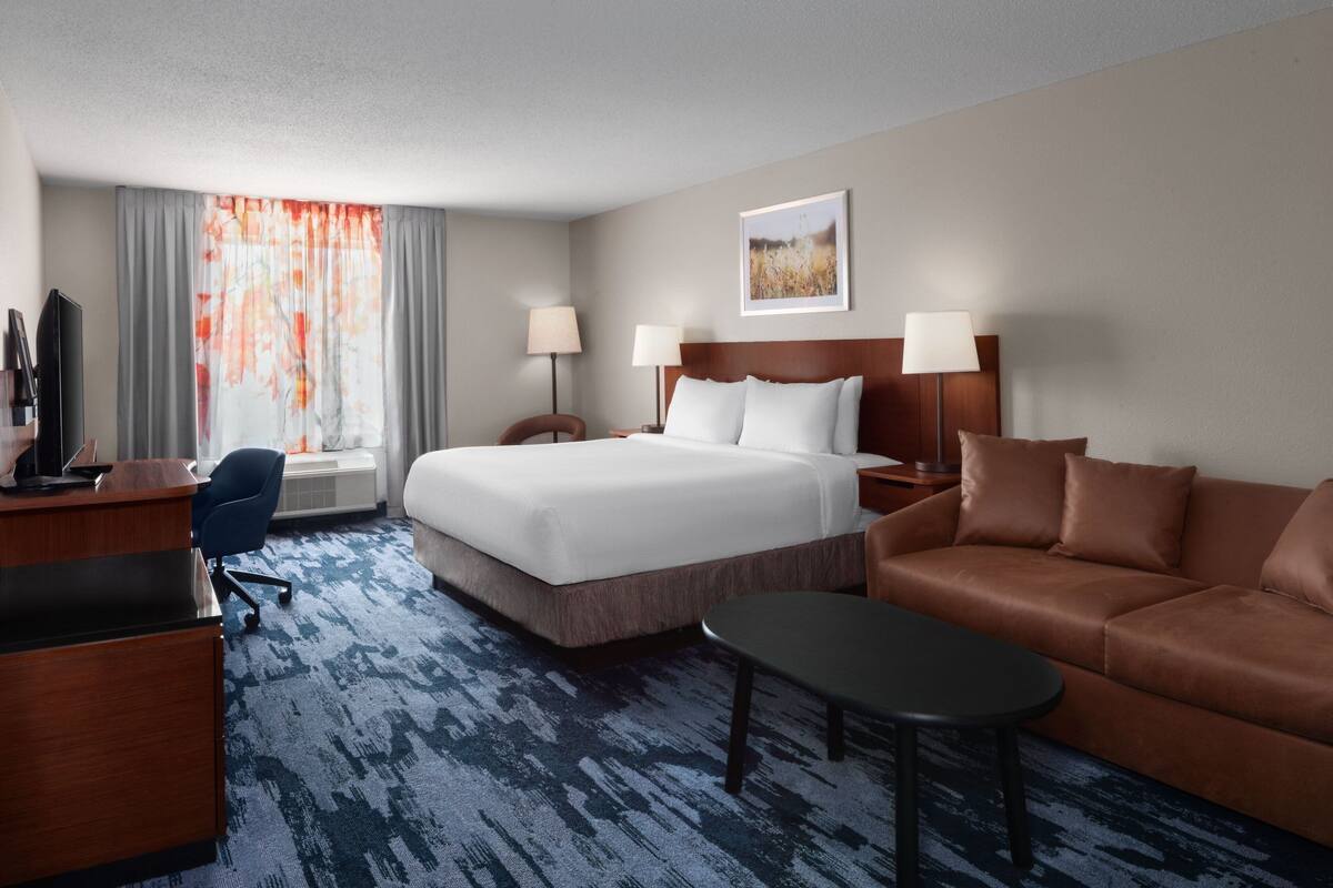 Une chambre d’hôtel avec un grand lit, un canapé, un bureau et une télévision.