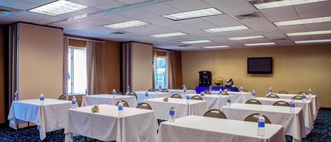 A conference room with multiple tables, each with a water bottle, arranged in rows.