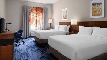 A hotel room with two beds, a desk, a chair, and a TV.