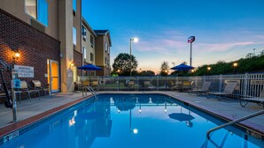 A swimming pool with a lifeguard stand, a sign indicating no lifeguard on duty, and a fenced area with lounge chairs and umbrellas. - Fairfield Inn by Marriott Charlotte Mooresville (Mooresville)