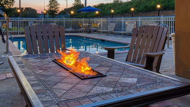 A poolside area with a fire feature on a table, surrounded by chairs. - Fairfield Inn by Marriott Charlotte Mooresville (Mooresville)