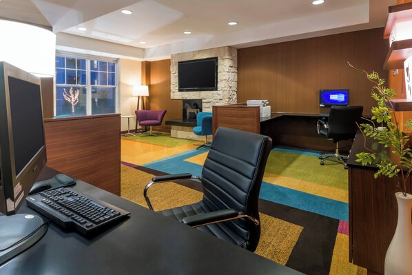 Una habitación de hotel moderna con escritorio, ordenador y zona de estar.