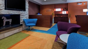A reception area with a stone wall, a flat-screen TV, a reception desk, and colorful chairs.