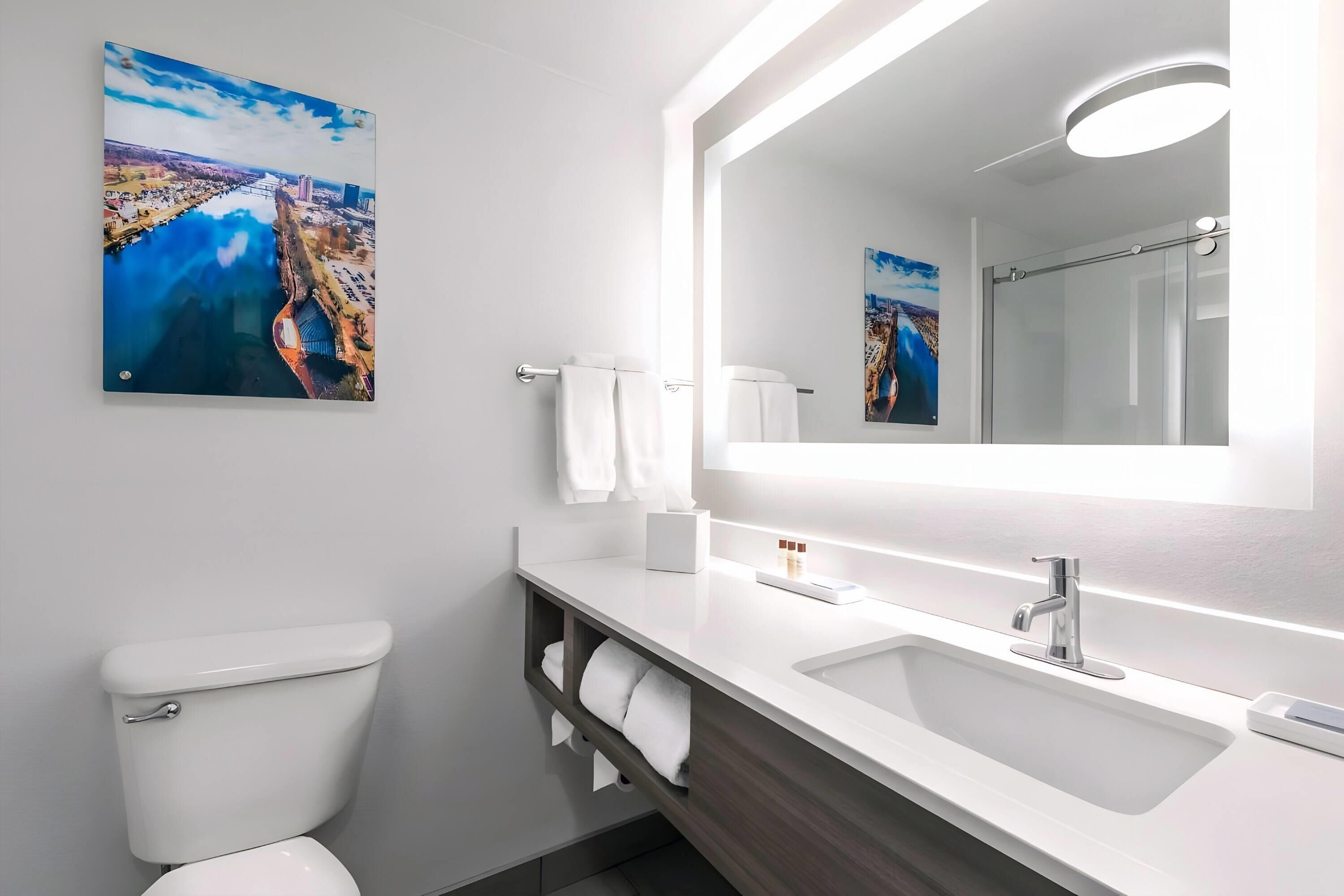 A modern bathroom with a white sink, a large mirror, and a toilet.