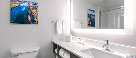 A modern bathroom with a white sink, a large mirror, and a toilet.