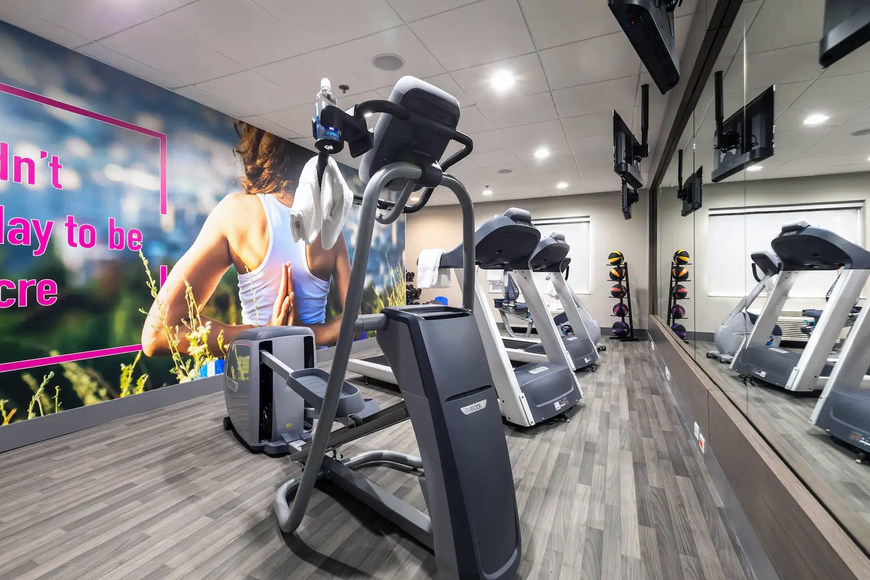 Un gimnasio con cintas de correr, bicicletas estáticas y un cartel motivacional en la pared.