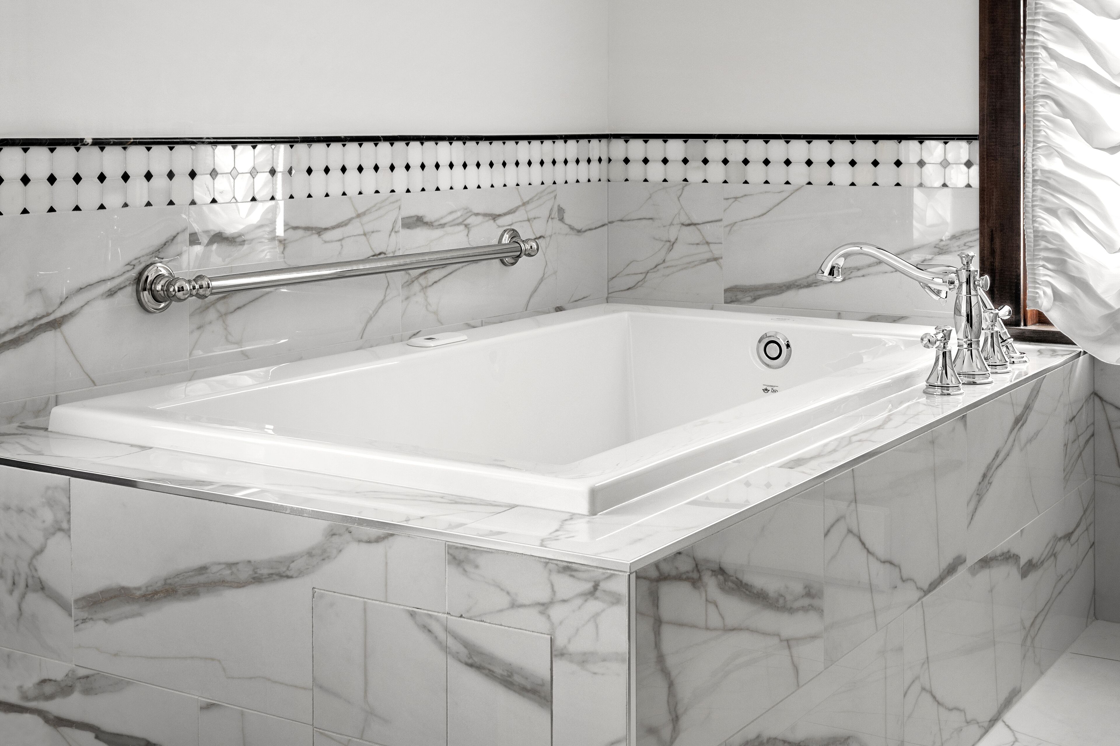 Un baño moderno con una bañera de mármol, cabina de ducha con mampara de cristal y pared de azulejos blancos con un detalle decorativo.