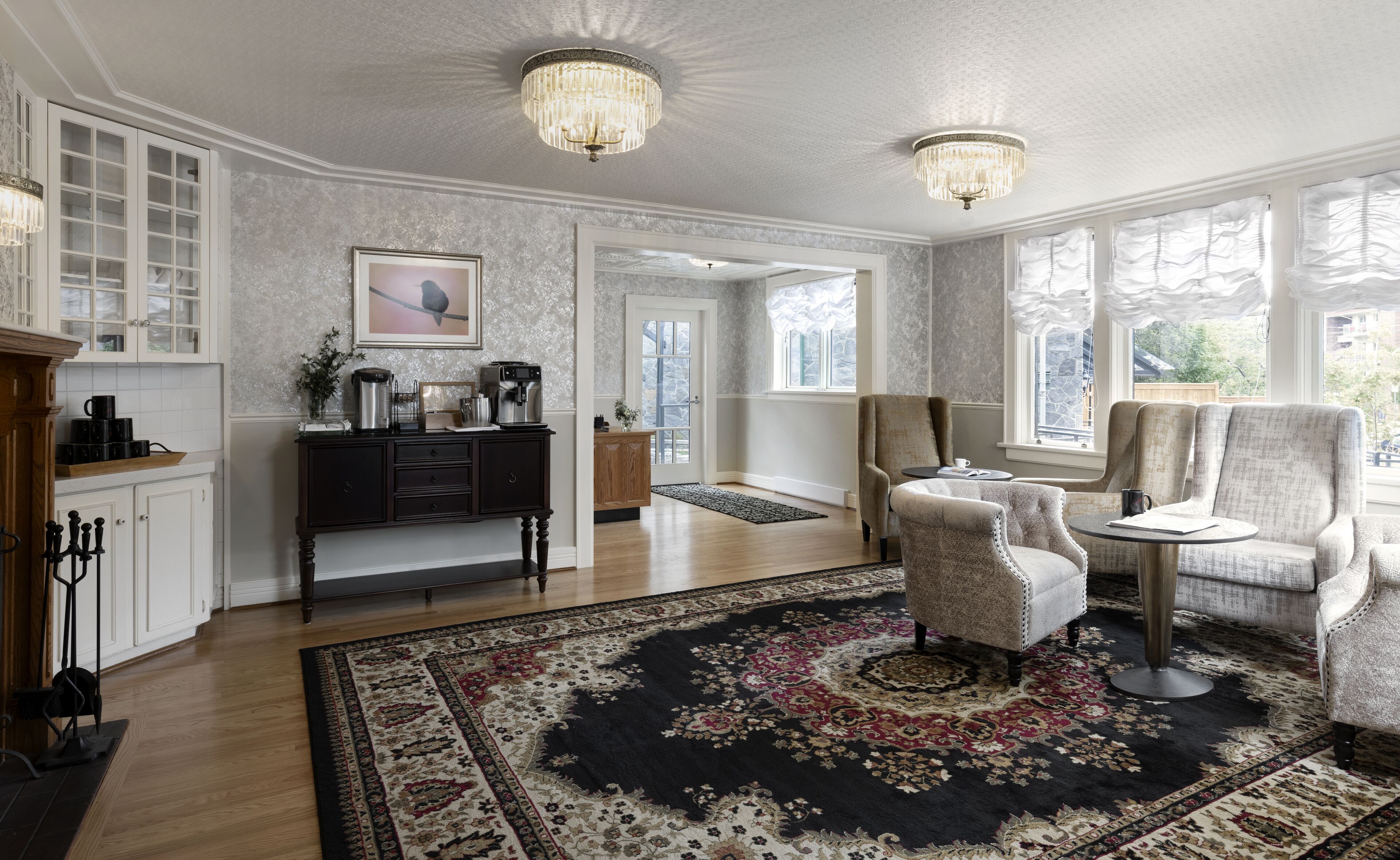 Un salon spacieux agrémenté d’un grand tapis, de deux fauteuils, d’une table basse et d’un lustre.