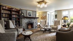 A cozy living room with a stone fireplace, bookshelves, comfortable seating, and a decorative rug. - Abigail's Hotel (Victoria)