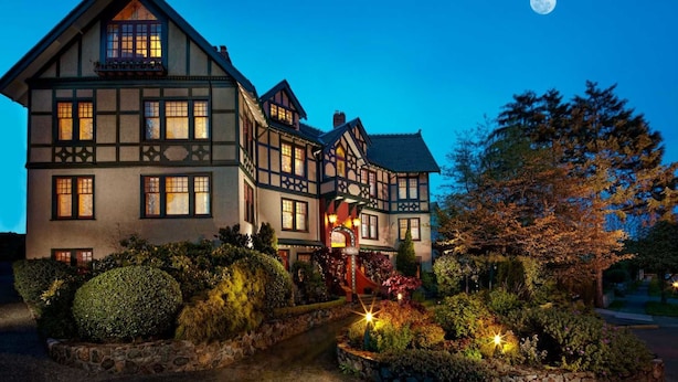 A traditional half-timbered building with multiple windows, a well-lit entrance, and a landscaped garden with stone pathways. - Abigail's Hotel (Victoria)
