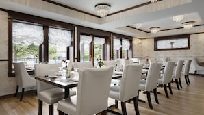 A dining area with a long table, multiple chairs, and large windows with sheer curtains. - Abigail's Hotel (Victoria)