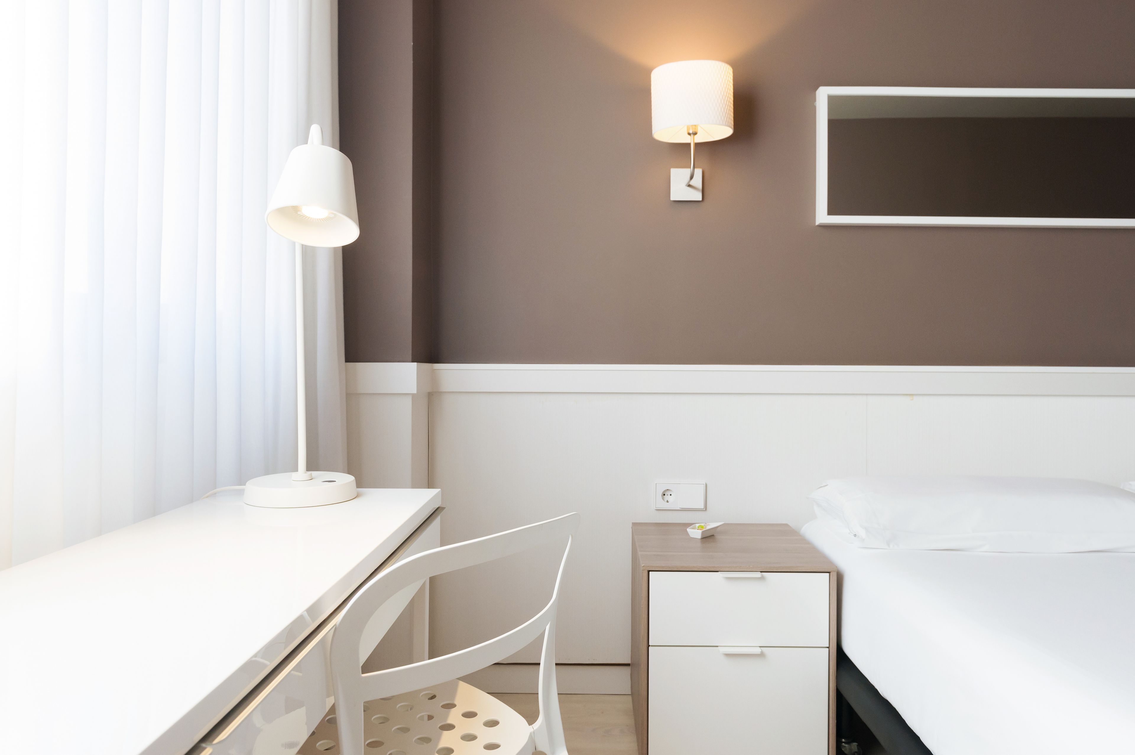 Une chambre d’hôtel équipée d’un bureau, d’une chaise, d’une table de chevet et d’un lit.