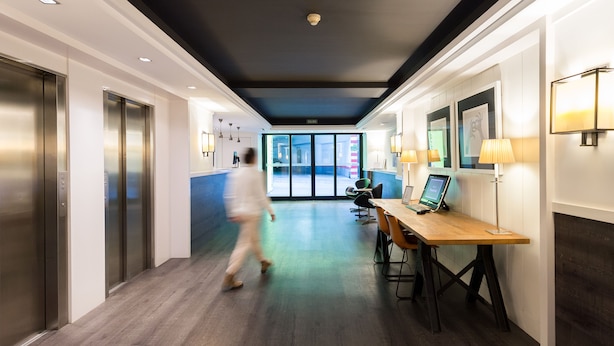 En modern hotellobby med en lång korridor, hissar, en receptionsdisk och utsikt över omgivningarna.