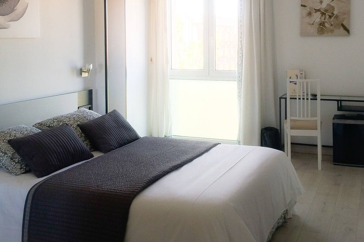 A bedroom with a bed, a desk, and a chair.