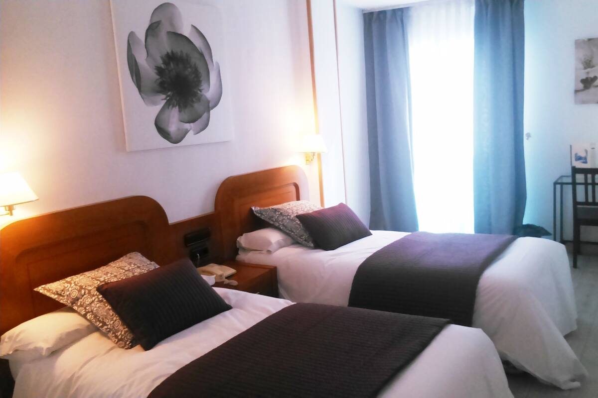 A hotel room with two beds, a desk, and a chair.