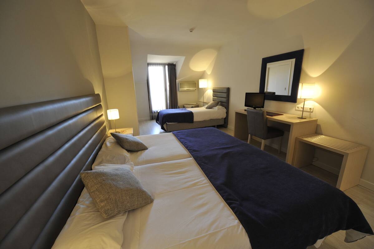 Een hotelkamer met een bed, bureau, stoel en een spiegel.