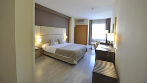 Een hotelkamer met een groot bed, nachtkastjes, een bureau en een stoel.