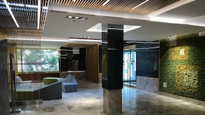 Een moderne lobby met een groene wand, zithoek en een houten lambrisering.