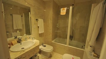 A bathroom with a marble sink, toilet, and a glass-enclosed shower.