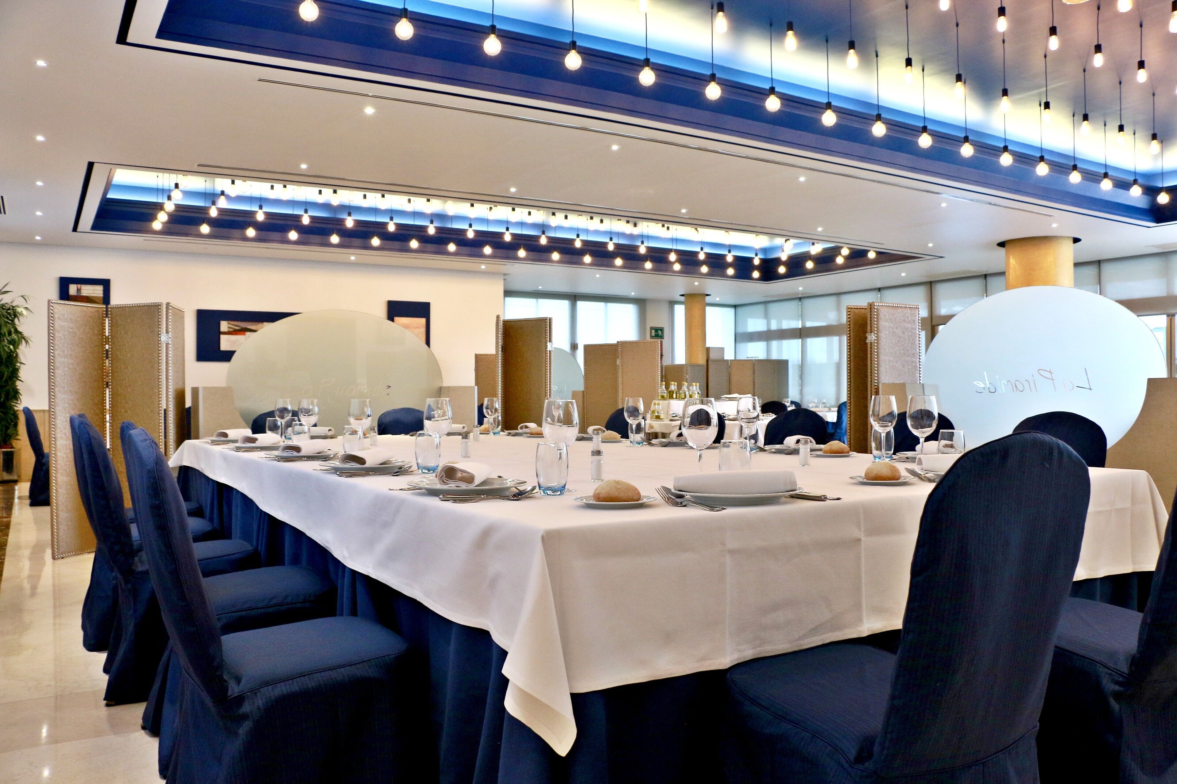 A conference room with a long table set for a meeting, surrounded by chairs.