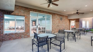 Ein Außenbereich mit Terrasse, Ziegelmauern, Glastüren und Deckenventilatoren.