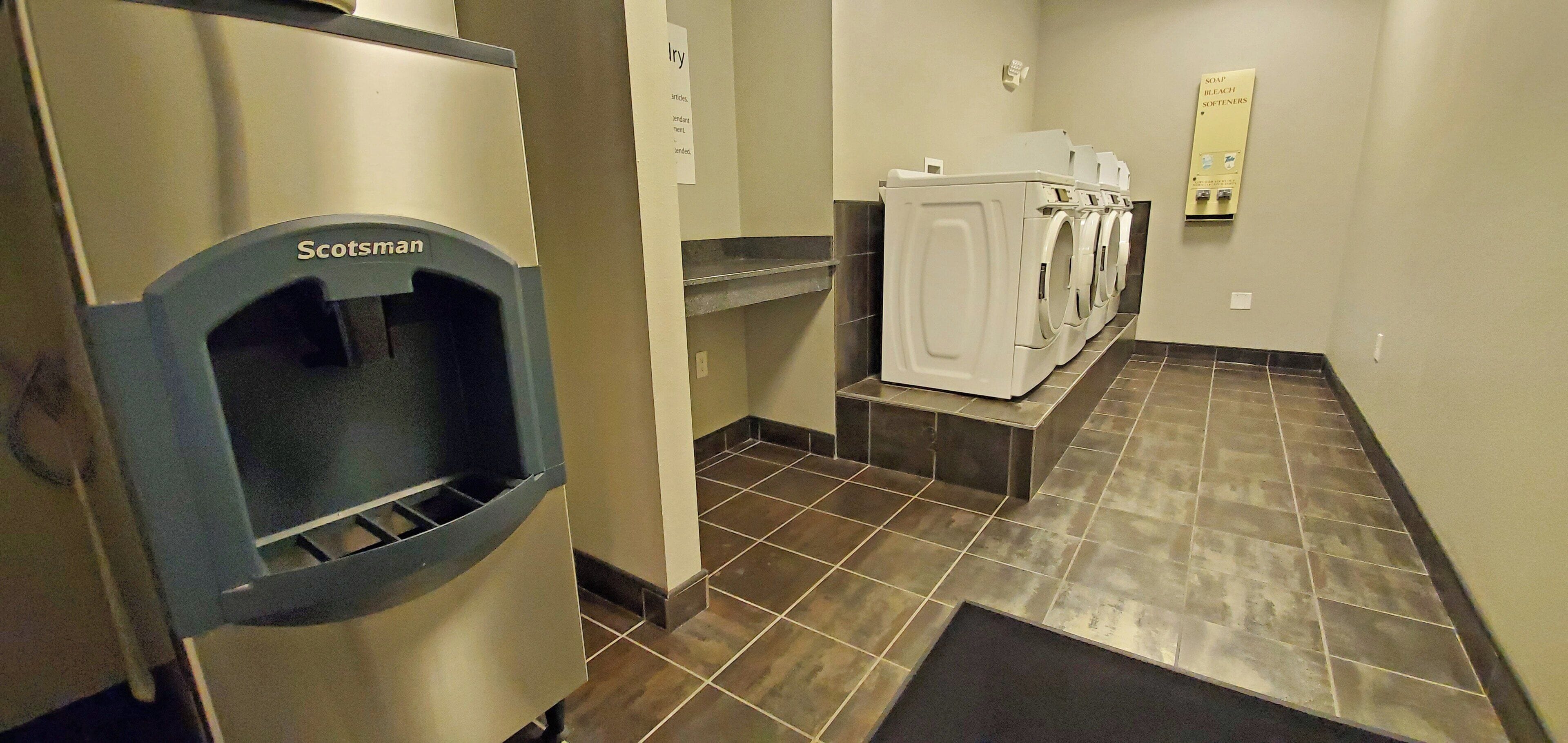 A restroom with a Scotman hand dryer, a soap dispenser, and a urinal.