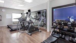 Ein Fitnessraum mit Laufbändern, Crosstrainern und einer Bank.