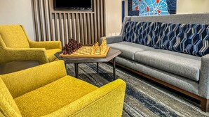 Ein modernes Wohnzimmer mit Schachbrett, einer Couch und zwei Sesseln.
