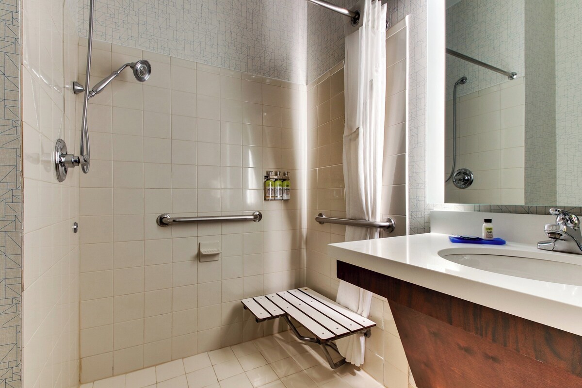 Une salle de bain équipée d’une douche, d’un lavabo, d’un miroir et d’un porte-serviettes.