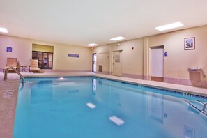 An indoor swimming pool with a lifeguard sign, a door, and a chair.