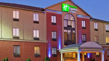 Un hotel Holiday Inn Express con fachada de ladrillo, grandes ventanales y una entrada central con porche cubierto.