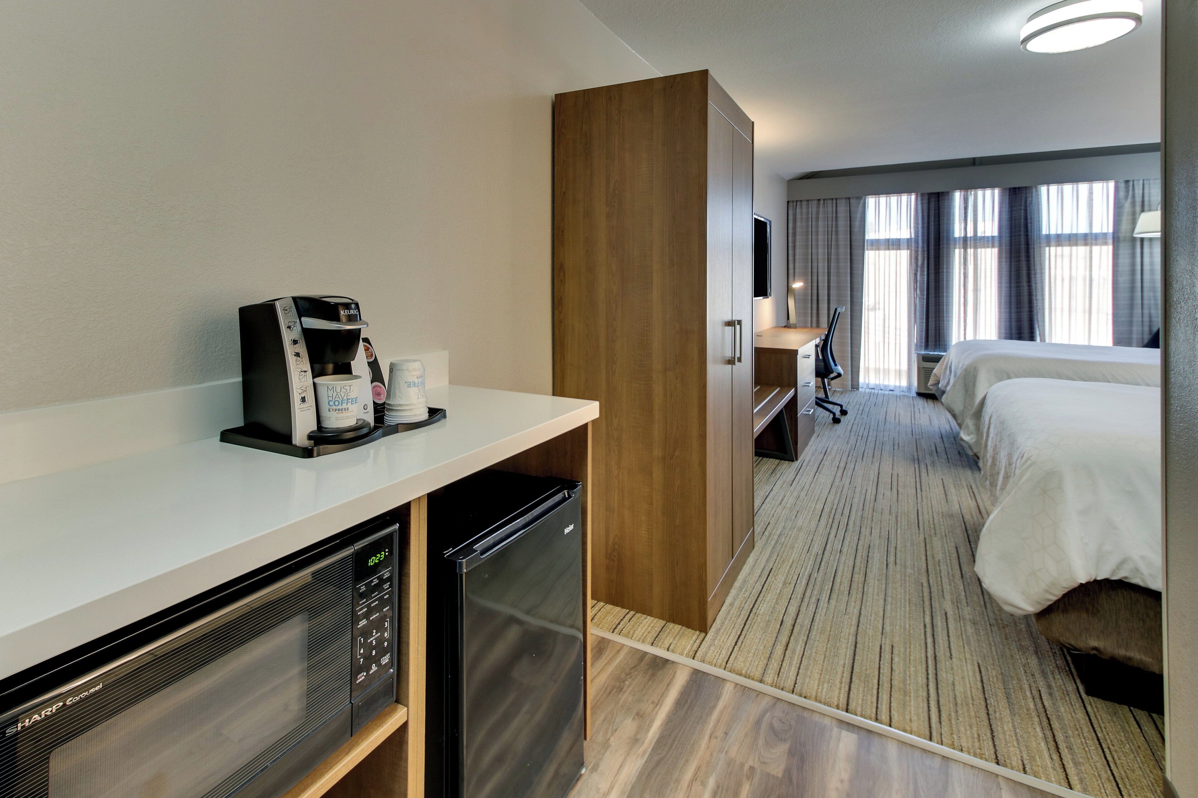 Habitación de hotel con kitchenette, cama, escritorio y televisión.