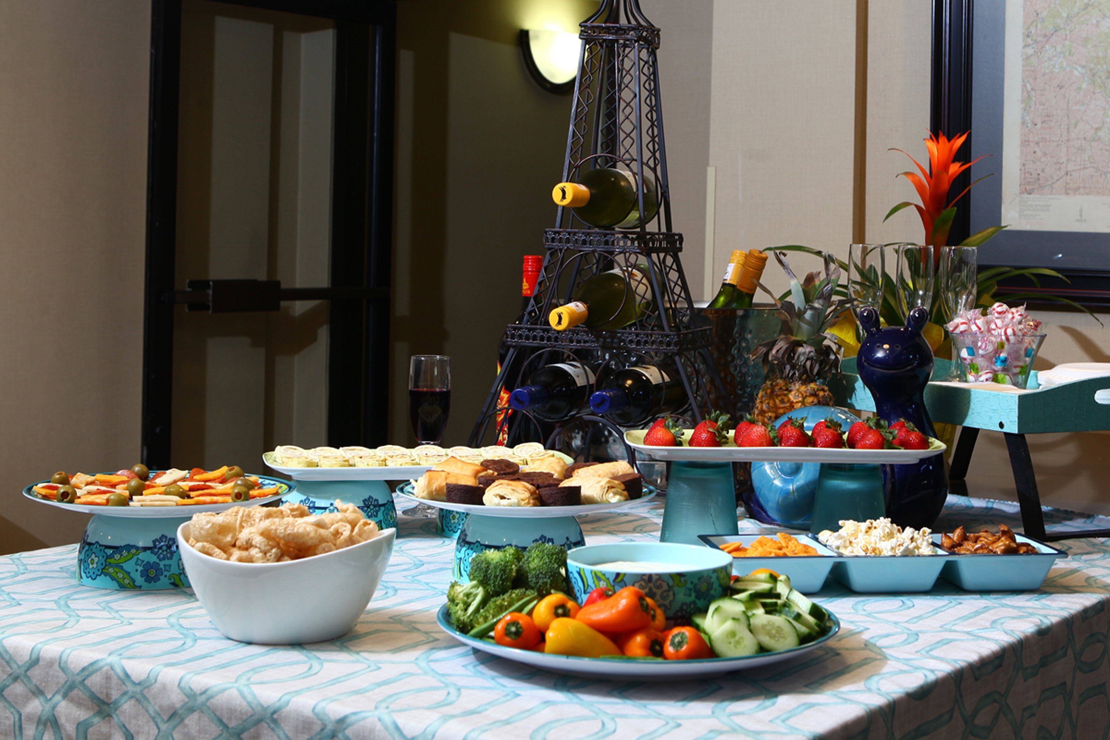 A buffet table with various food items, including fruits, vegetables, and pastries.