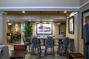 A dining area with a table, chairs, and a large framed picture on the wall. - Holiday Inn Express Atlanta - Emory University Area by IHG (Decatur)