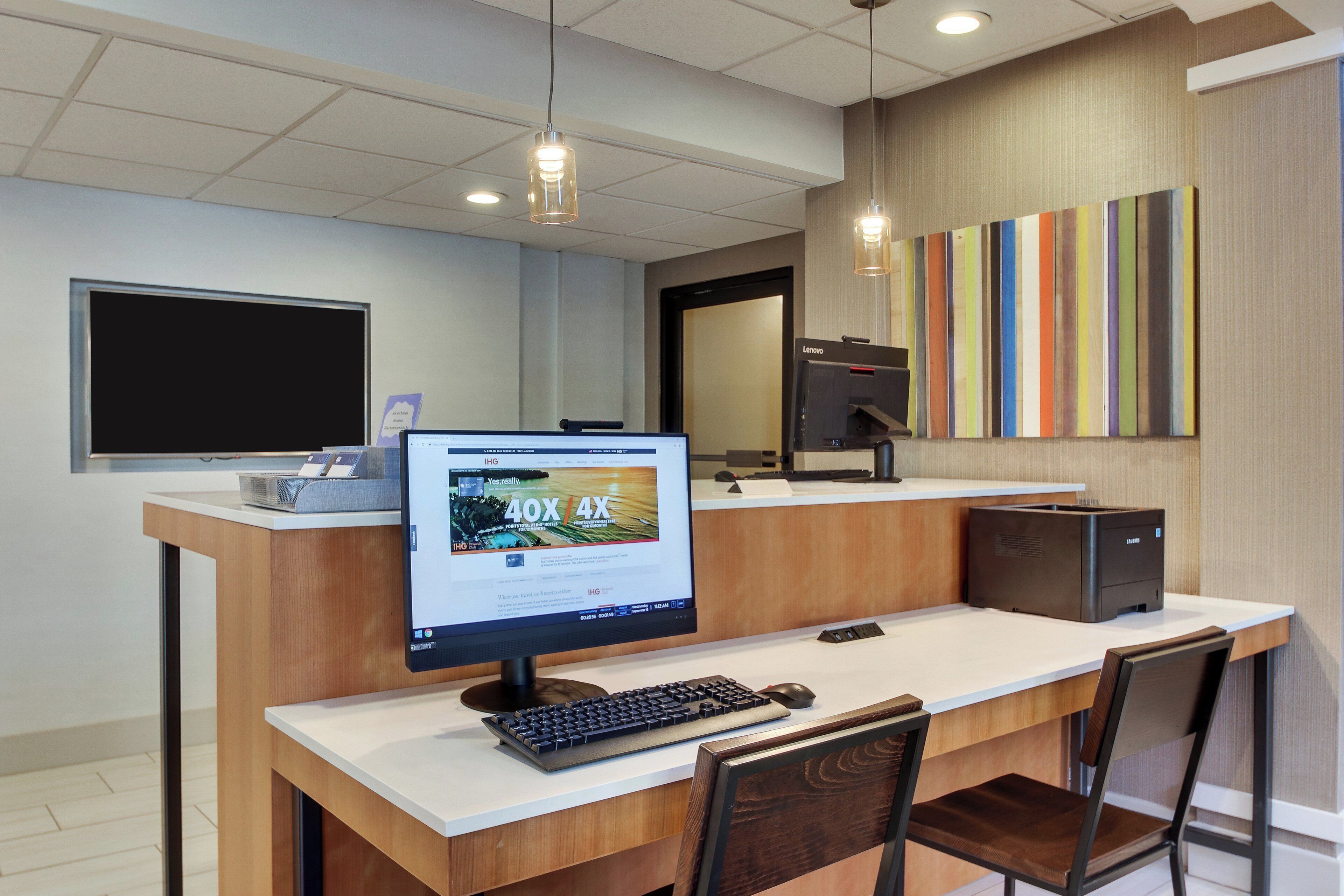 A modern reception desk with a computer monitor, keyboard, and mouse.