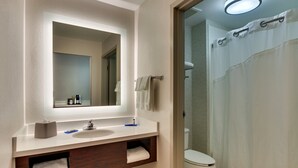 A bathroom with a white sink, mirror, and toilet. There is a towel rack above the sink and a shower curtain visible in the background.