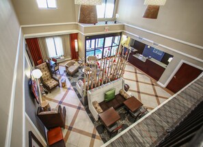 A hotel lobby with a check-in counter, seating area, and a decorative plant arrangement. - Holiday Inn Express Atlanta - Emory University Area by IHG (Decatur)