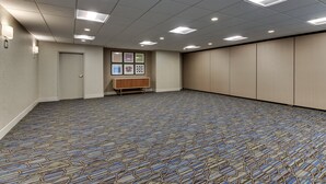 A conference room with a patterned carpet, recessed ceiling lights, a wooden bench, and a door.