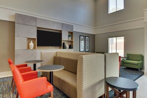 A modern lounge area with a sofa, two round tables, and a green armchair. - Holiday Inn Express Atlanta - Emory University Area by IHG (Decatur)