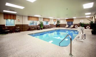 An indoor swimming pool with a lifeguard station, seating area, and potted plants.