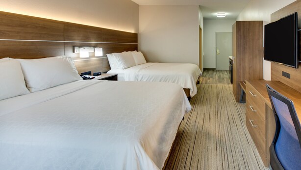 A hotel room with two beds, a TV, and a wooden headboard.