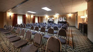 A conference room with rows of chairs, a stage, and a seating area with tables. - Holiday Inn Express Atlanta - Emory University Area by IHG (Decatur)