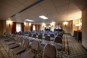 A conference room with rows of chairs, a stage, and a seating area with tables. - Holiday Inn Express Atlanta - Emory University Area by IHG (Decatur)