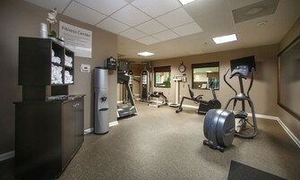 Una palestra con attrezzature per esercizi, un dispenser d'acqua e una sveglia appesa al muro.