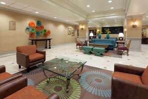 A lobby with a seating area, a glass coffee table, and a decorative wall.