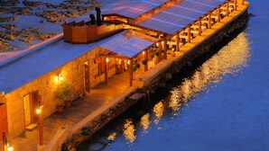 A waterfront building with a covered walkway, stone walls, and outdoor lighting. - Byblos Sur Mer (Byblos)