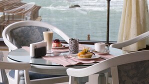 A table with a lamp, a cup, a plate with food, and a view of the ocean. - Byblos Sur Mer (Byblos)